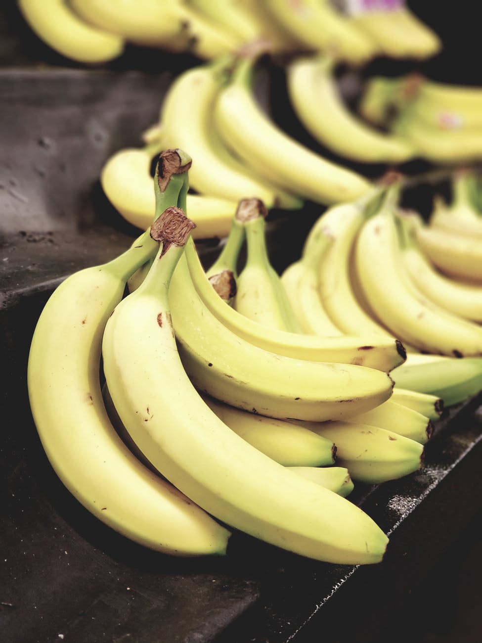 selective focus photo of bunch of bananas on black surface